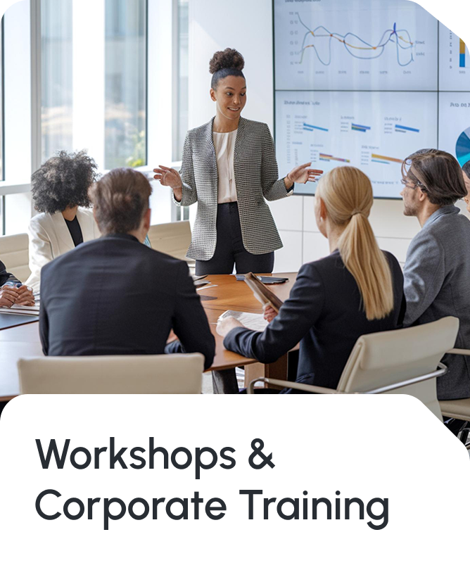 Corporate training and workshop marketing image featuring a professional woman in a light cardigan presenting to a seated diverse team of executives and professionals in a modern conference room with large windows and financial charts displayed on screens in the background. Text reads 'Workshops & Corporate Training', representing Star Trak Investments LLC's commitment to employee development, financial literacy workshops, organizational training, and professional development programs