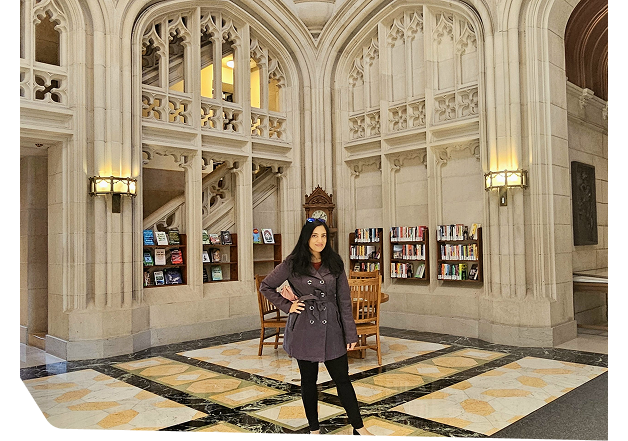 Elegant interior photograph of a grand historic library or institutional building with ornate Gothic or Beaux-Arts architectural details, featuring tall carved stone columns, elaborate ceiling patterns with decorative molding, arched windows with warm lighting, and ornamental railings with bookshelves visible. Used to represent Star Trak Investments LLC's commitment to knowledge, institutional stability, financial heritage, and professional excellence on the company's About page