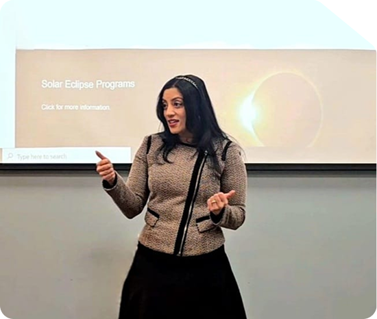 Angel Mary motivational speaker presenting on stage in front of a Solar Eclipse Programs slide